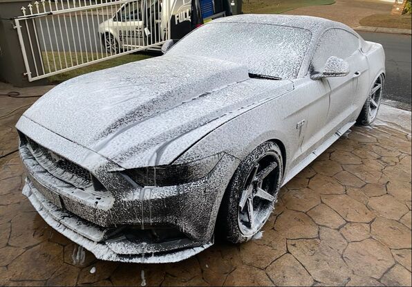 a mustang covered in the snow foam spray before a wash
